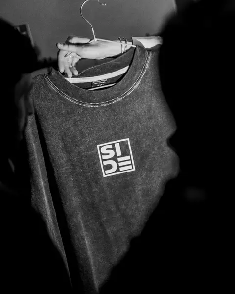 Camiseta gris lavada con el logo SIDE, colgada en una percha